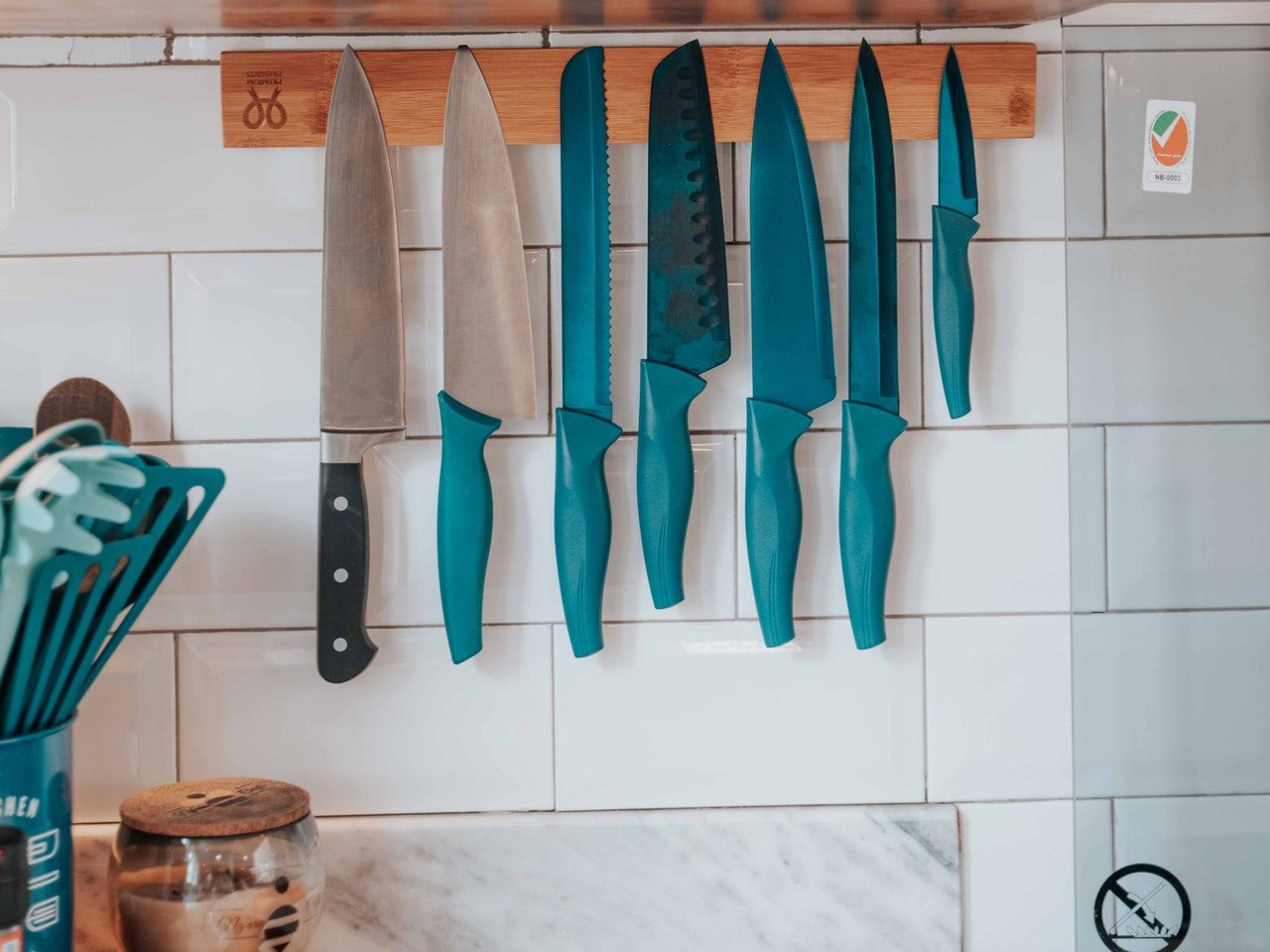 A set of knives hanging on a magnetic strip to maximize space for small kitchen storage ideas