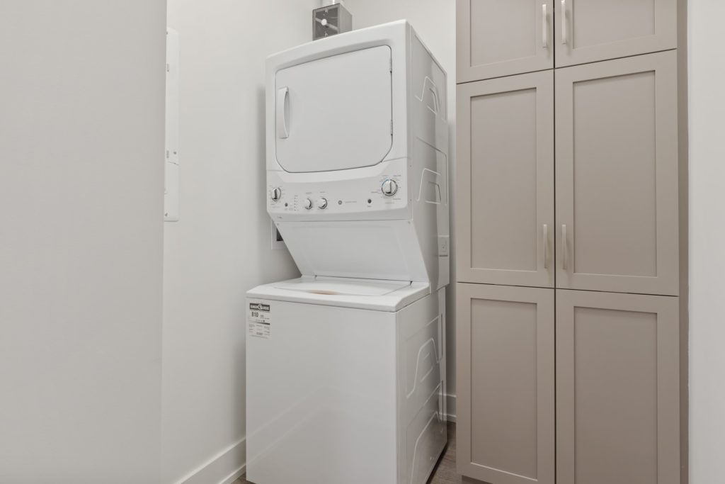 Small laundry room ideas: Stackable washer and dryer next to a cabinet.